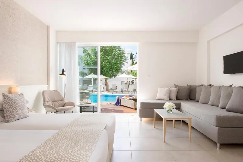 Espace de vie lumineux avec canapé d'angle et accès à une piscine.