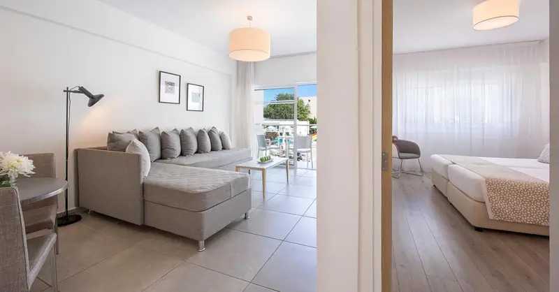 Espace de vie lumineux avec canapé d'angle et chambre attenante.