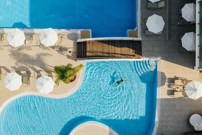 Vue aérienne d'une piscine avec des transats et parasols.