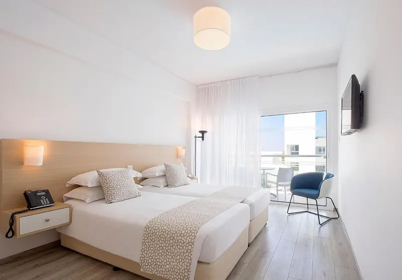 Chambre lumineuse avec un lit double et un accès à un balcon.