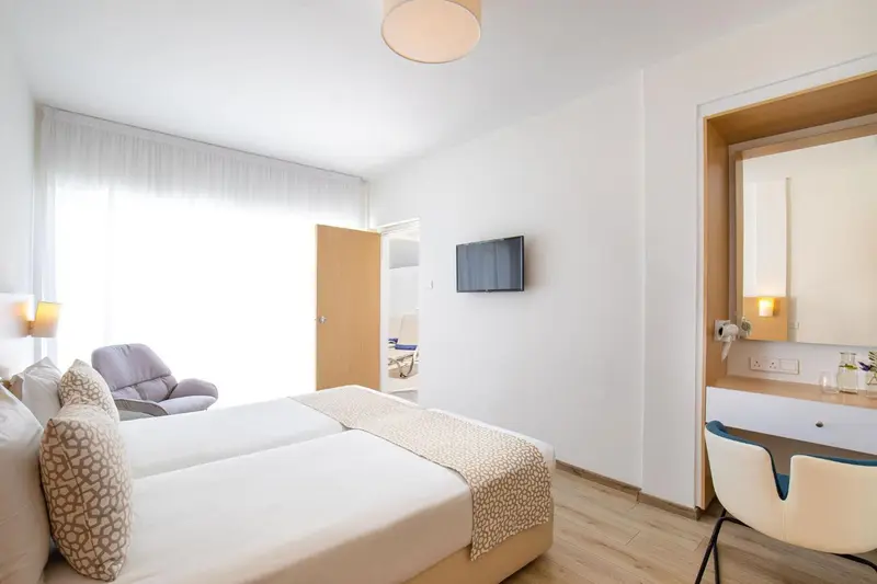 Une chambre lumineuse avec un lit double et un fauteuil.