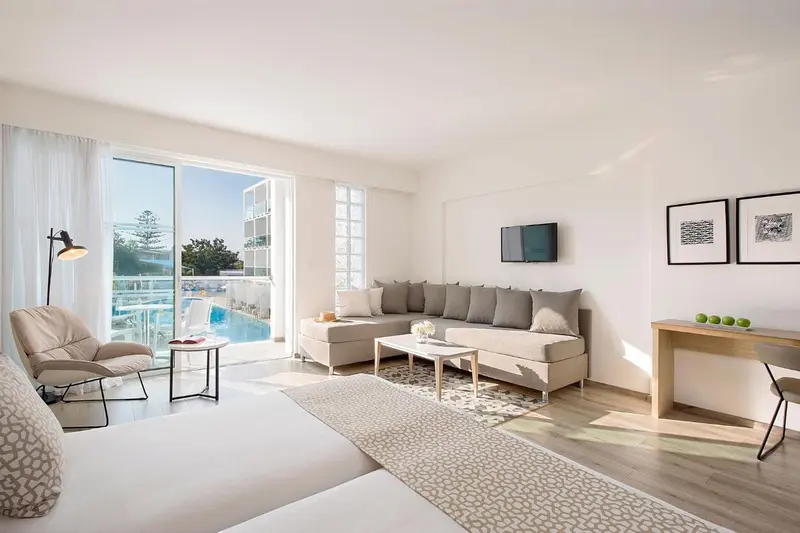 Espace de vie lumineux avec canapé d'angle et vue sur une piscine.