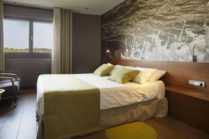Une chambre lumineuse avec un grand lit et un mur décoré d'une image sous-marine.