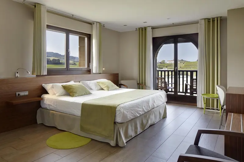 Une chambre lumineuse avec un grand lit et un accès à un balcon.