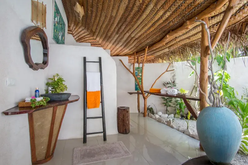 Salle de bain ouverte sur une végétation luxuriante.