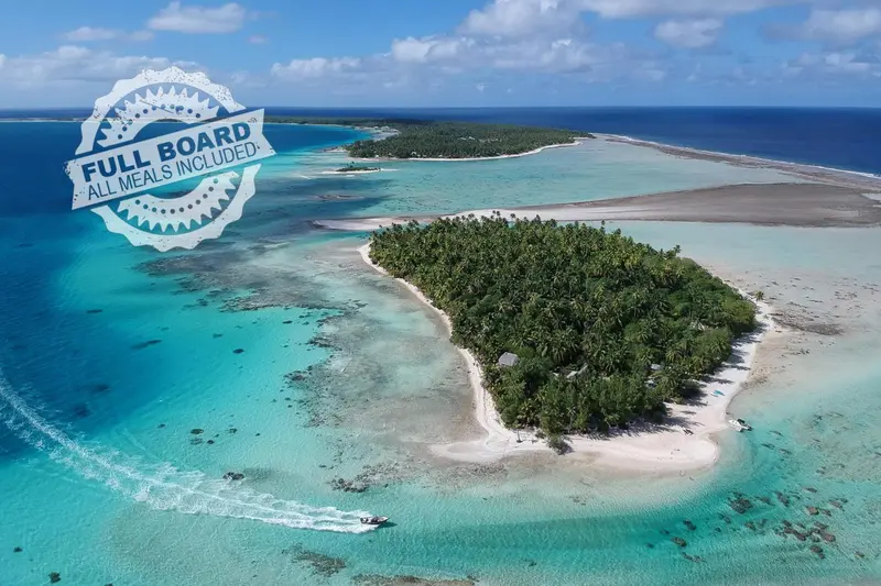 Vue aérienne d'une île tropicale bordée d'une plage de sable blanc et d'un lagon turquoise.
