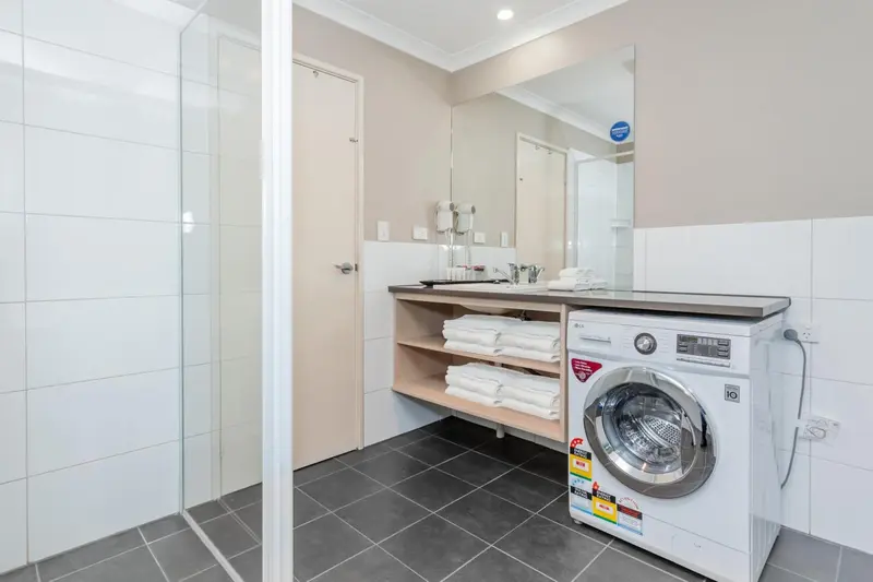 Une salle de bain moderne avec douche vitrée et machine à laver.