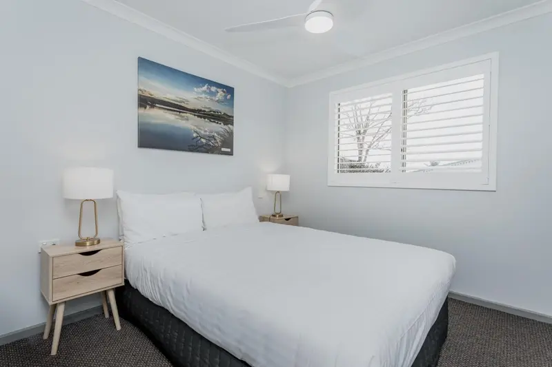 Une chambre lumineuse avec un grand lit et des tables de chevet.