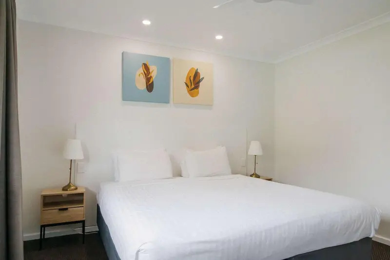 Une chambre lumineuse avec un grand lit recouvert de linge blanc.