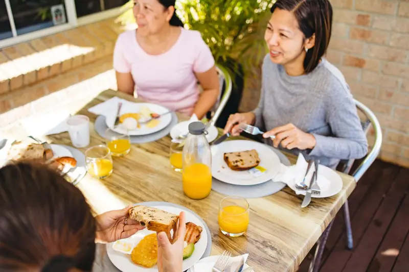 Des convives prennent leur repas sur une table en extérieur.