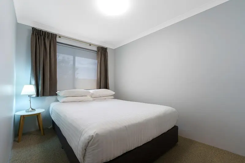 Une chambre lumineuse avec un lit double et une table de chevet.