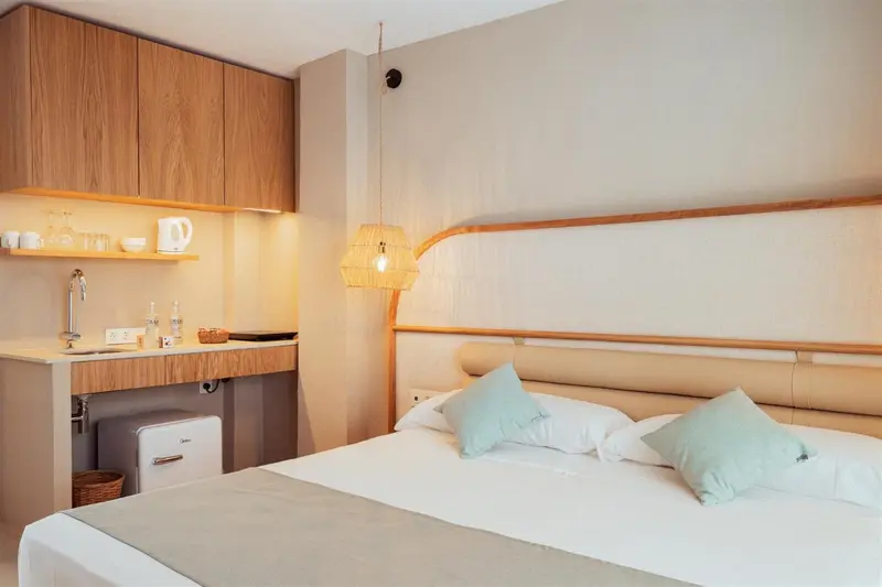 Une chambre lumineuse avec un coin cuisine et un lit confortable.