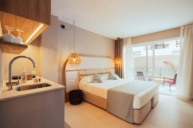 Une chambre lumineuse avec un lit et une kitchenette.