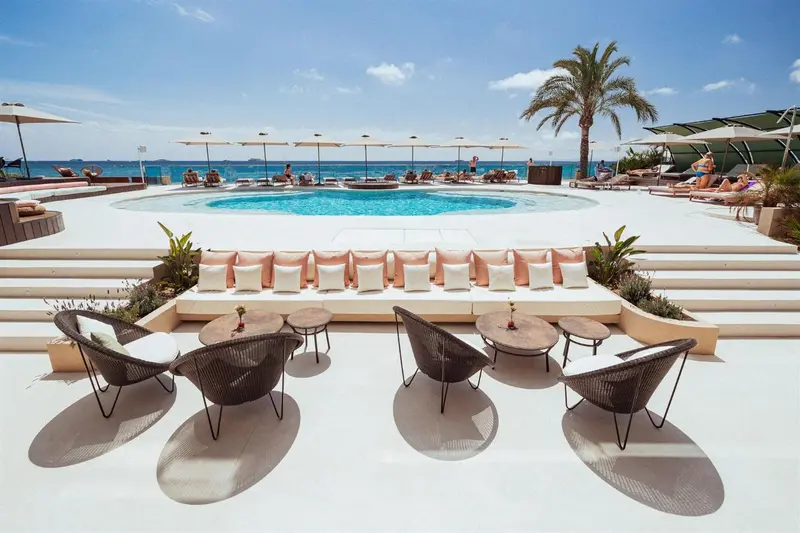 Espace de détente avec des transats et des canapés près d'une piscine.