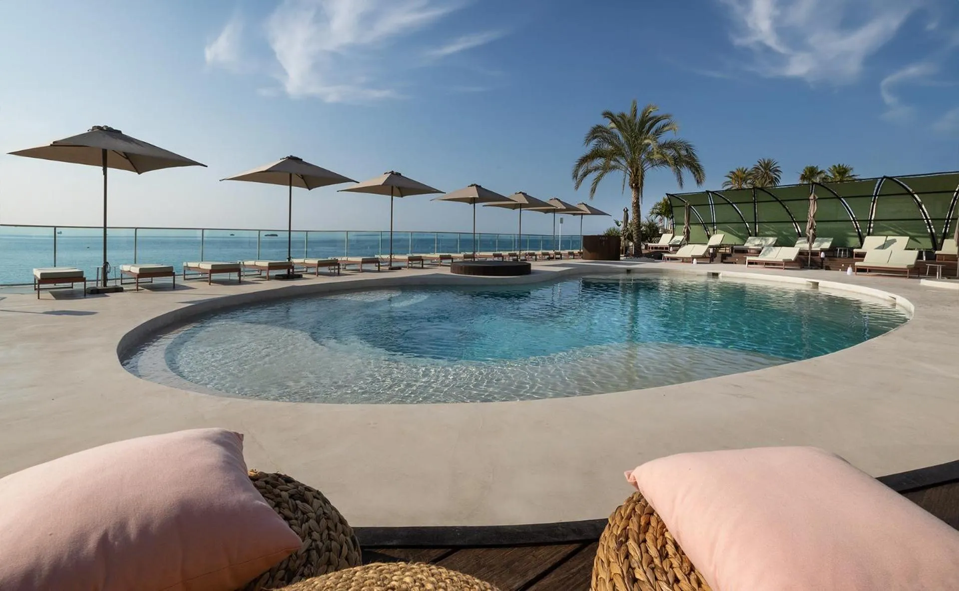 Terrasse avec piscine et transats en bord de mer.