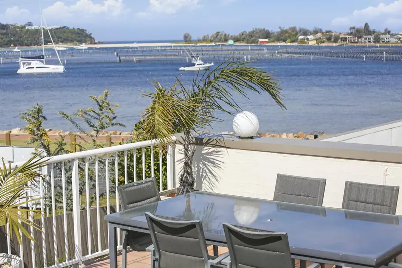 Terrasse avec mobilier de jardin donnant sur une baie abritée.