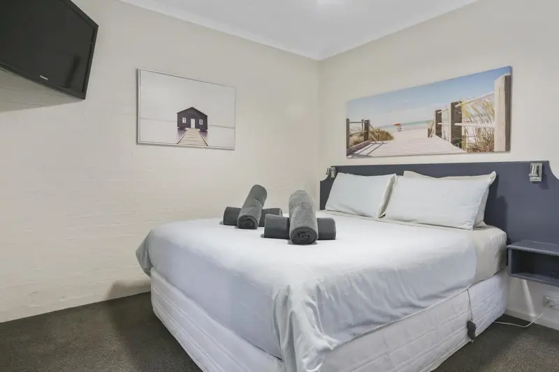 Une chambre lumineuse avec un grand lit et une décoration murale.