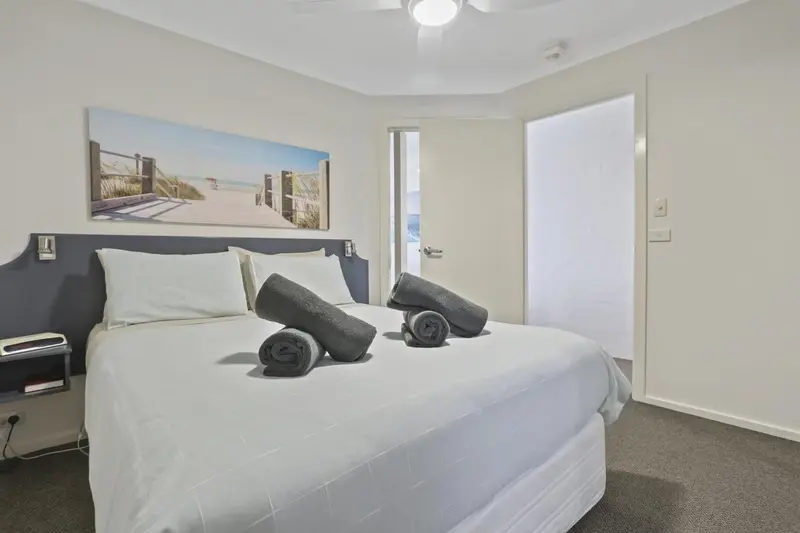 Une chambre lumineuse avec un grand lit recouvert de draps blancs et de serviettes.