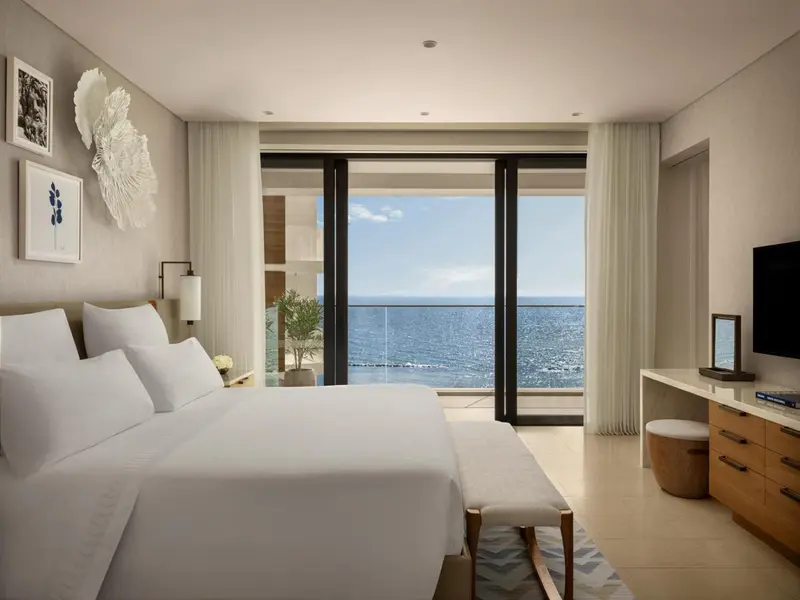 Une chambre lumineuse avec un grand lit donnant sur la mer.
