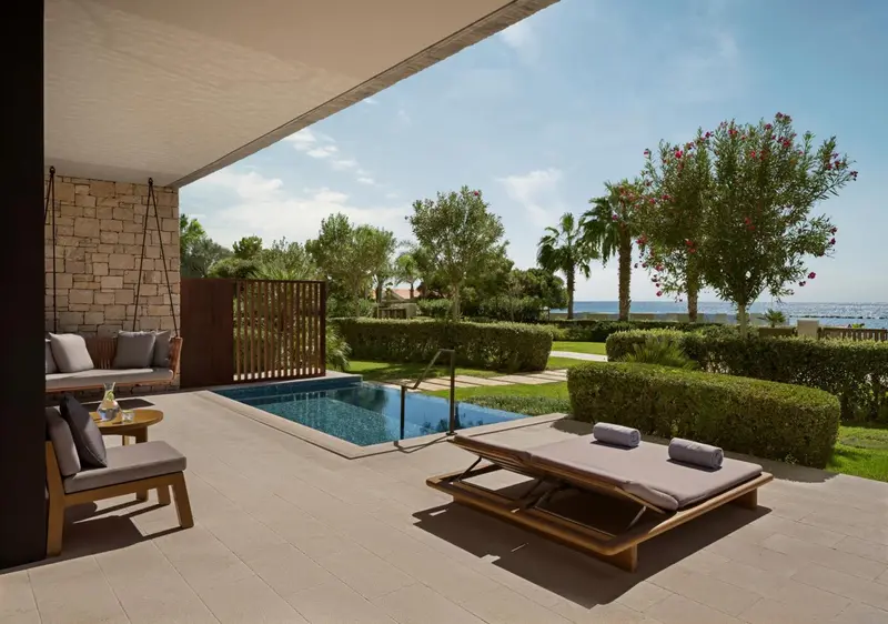 Terrasse avec piscine et mobilier de jardin face à la mer.