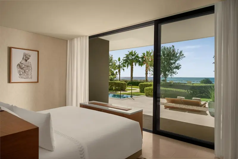 Une chambre lumineuse s'ouvre sur une vue verdoyante et la mer.