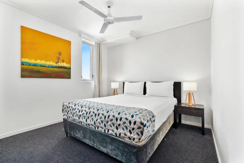 Une chambre lumineuse avec un grand lit recouvert d'une courtepointe décorative.