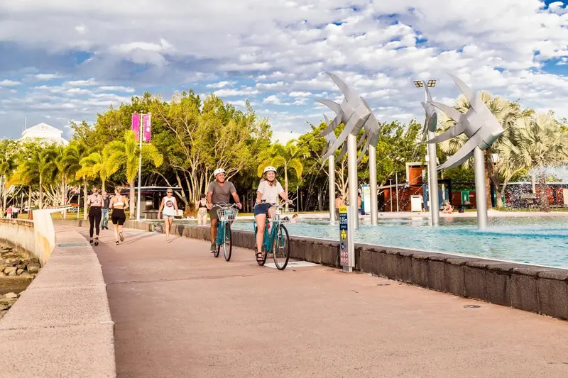 Des cyclistes et des piétons se promènent le long d'une promenade en bord de mer.