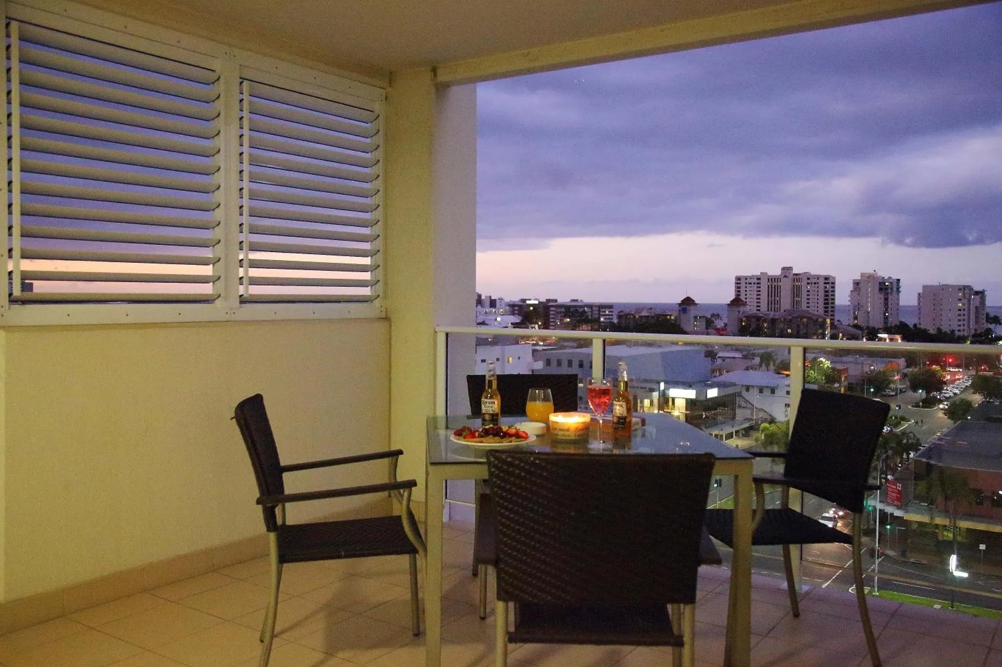 Une table avec des boissons et des en-cas est mise en scène sur une terrasse avec vue sur la ville.