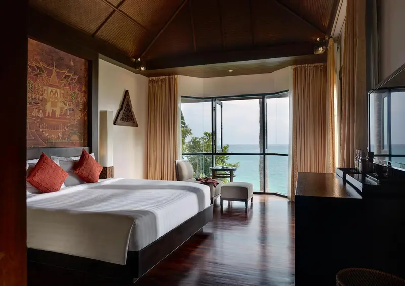 Chambre lumineuse avec un grand lit et une vue sur la mer.
