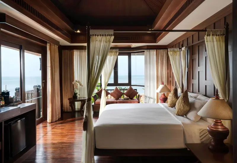 Chambre spacieuse avec un grand lit à baldaquin et vue sur la mer.