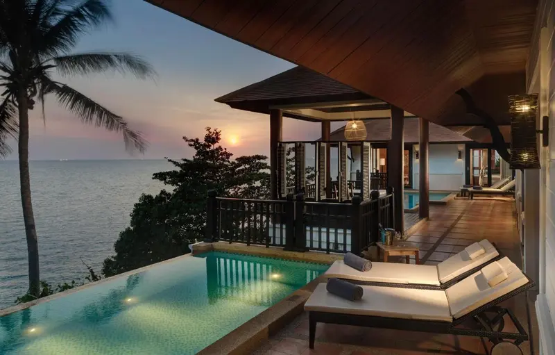 Terrasse avec piscine et vue sur la mer au coucher du soleil.