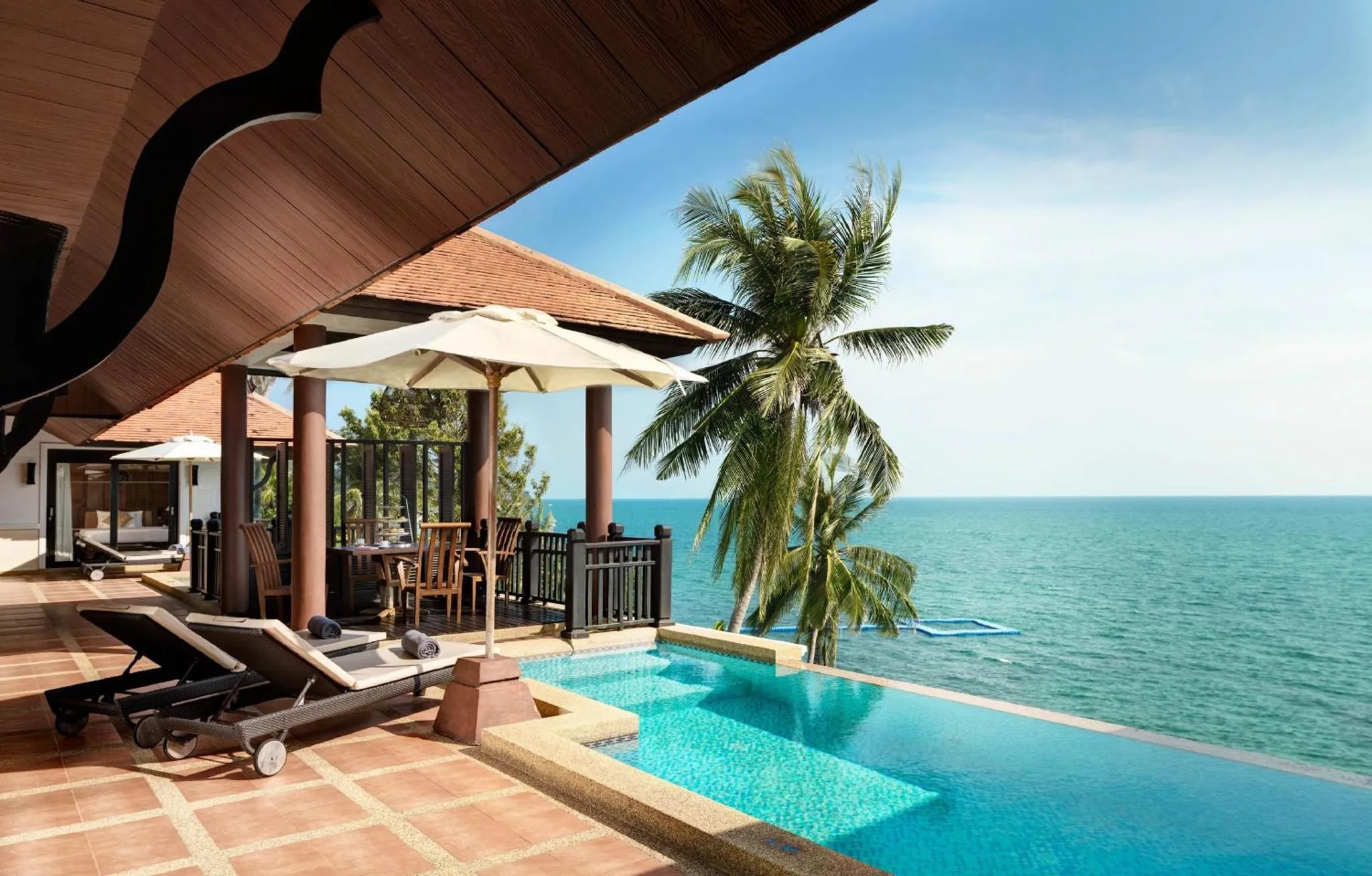Terrasse avec transats, piscine et vue sur la mer.