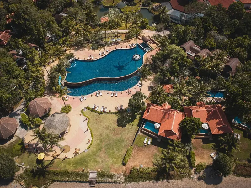 Vue aérienne d'un complexe hôtelier avec piscine et végétation luxuriante.