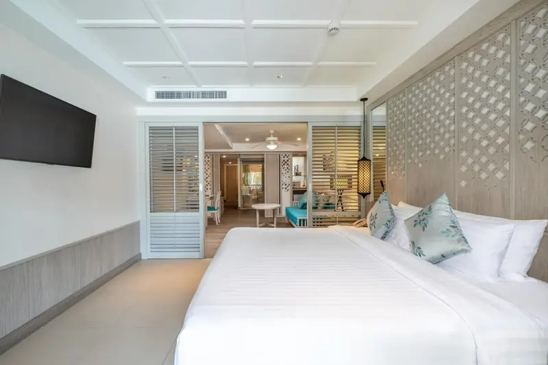 Une chambre lumineuse avec un grand lit et un accès à un espace de vie.