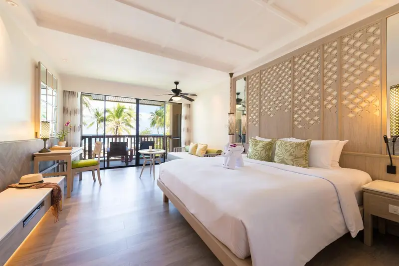 Une chambre lumineuse avec un grand lit et un accès à un balcon.