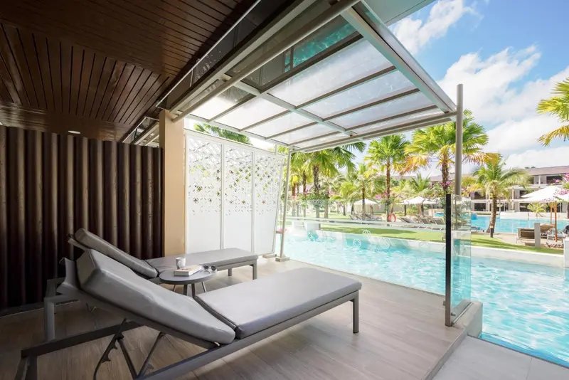 Deux transats gris invitent à la détente sur une terrasse ombragée avec vue sur une piscine.