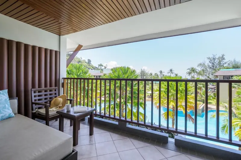 Terrasse aménagée avec salon et vue sur une végétation luxuriante et une piscine.