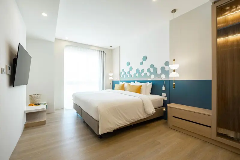 Une chambre lumineuse avec un grand lit et une décoration murale colorée.