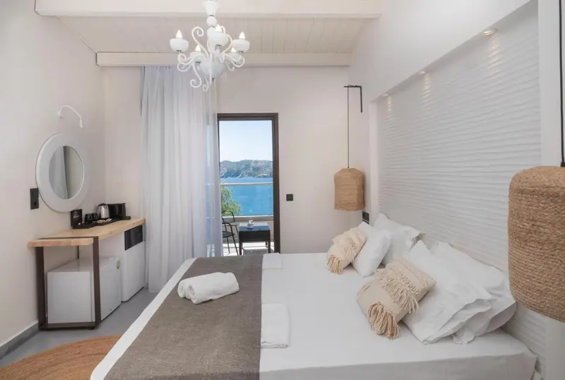Chambre lumineuse avec un lit double et une vue sur la mer.