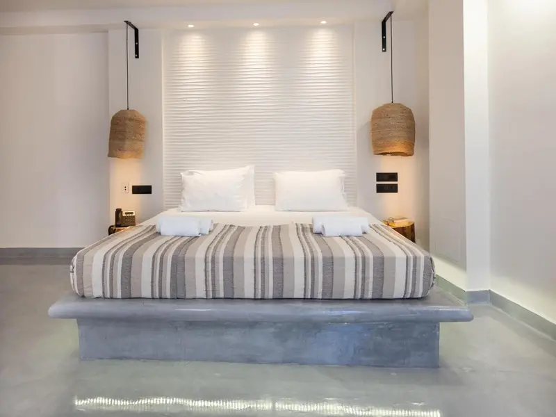 Une chambre lumineuse avec un grand lit recouvert d'une couette rayée.