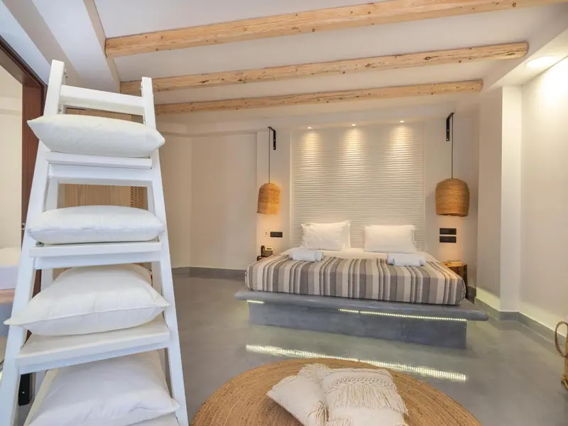 Une chambre lumineuse avec un lit double et un escalier en bois.