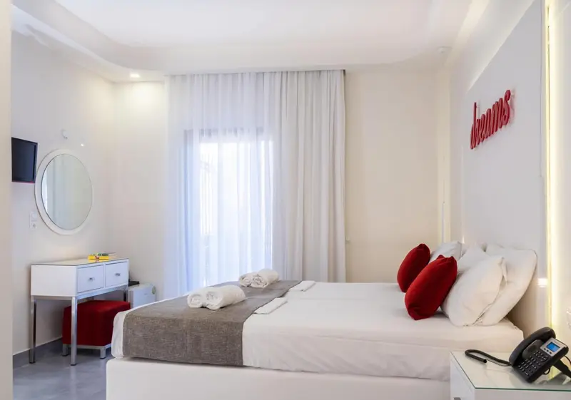 Une chambre lumineuse avec un grand lit et un coin coiffeuse.