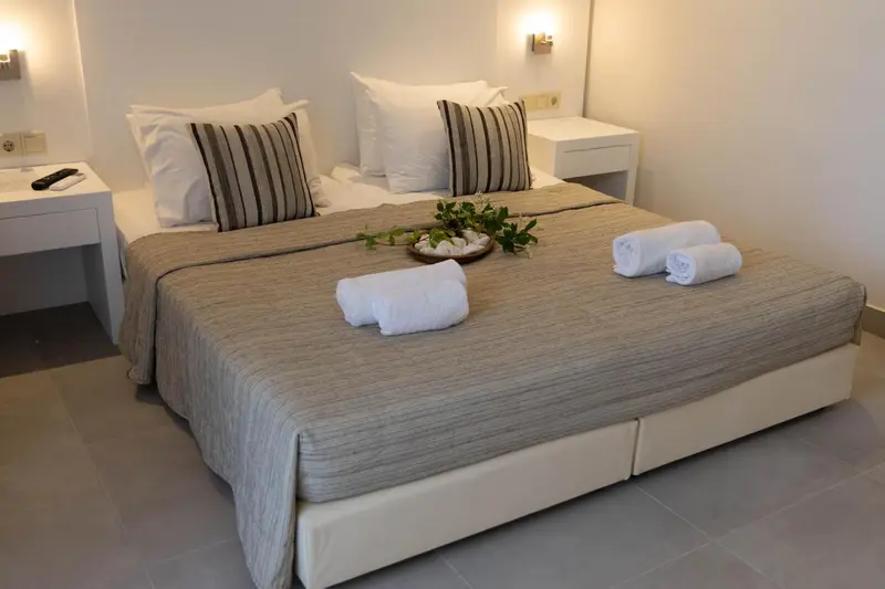 Une chambre lumineuse avec un grand lit recouvert d'une couverture et de coussins.