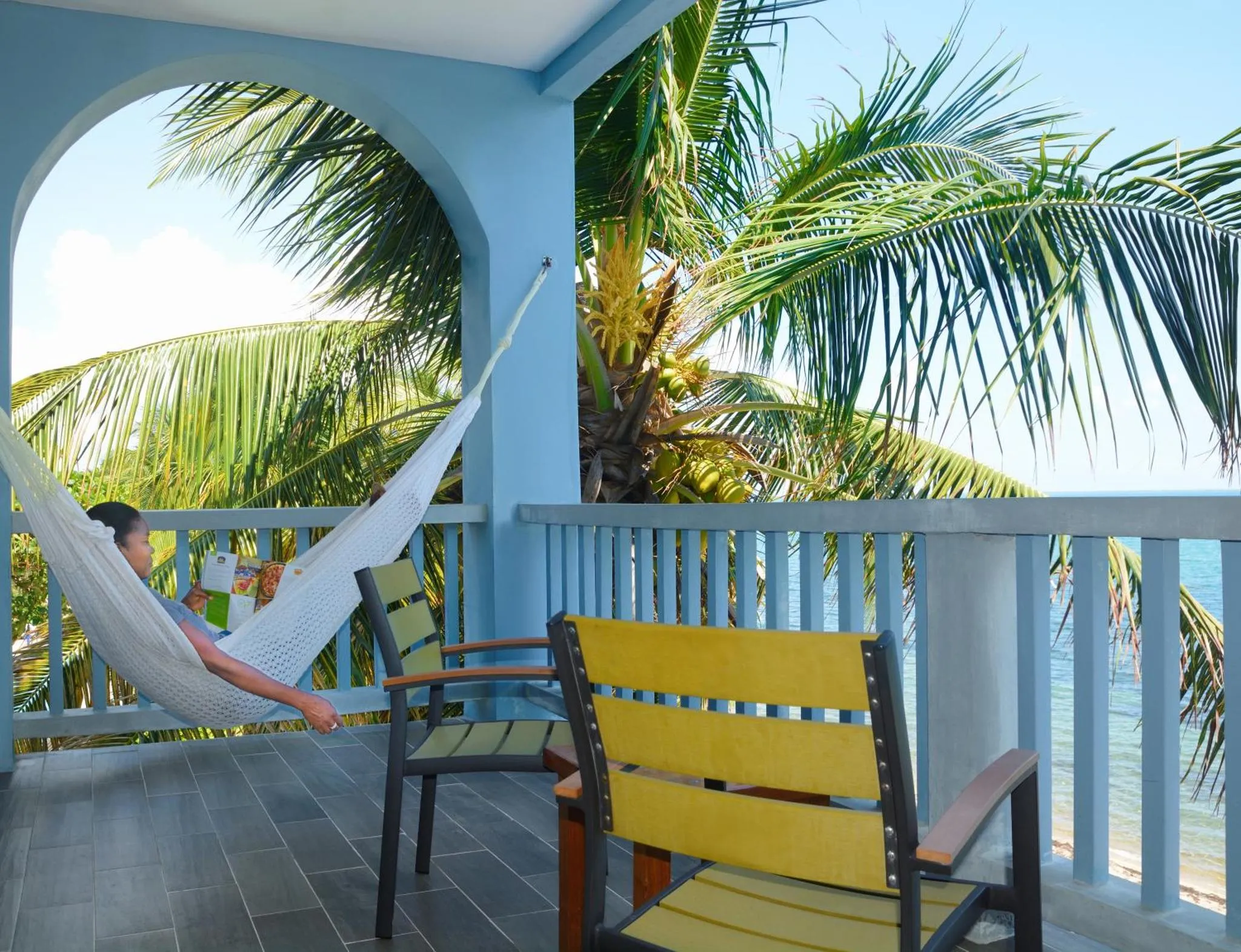 Une hamac est suspendu sur une terrasse avec des fauteuils et une vue sur la mer.