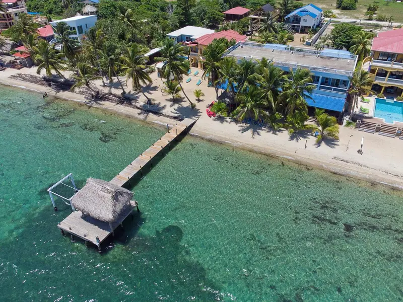 Vue aérienne d'un complexe hôtelier au bord de mer avec une plage et un ponton.