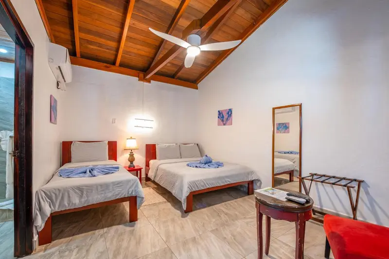 Une chambre lumineuse avec deux lits simples et un drapé bleu.