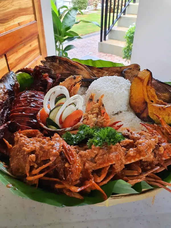 Assiette généreuse de fruits de mer et de riz, présentée sur une feuille de bananier.