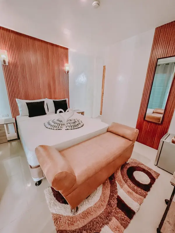 Une chambre lumineuse avec un lit double et un fauteuil.