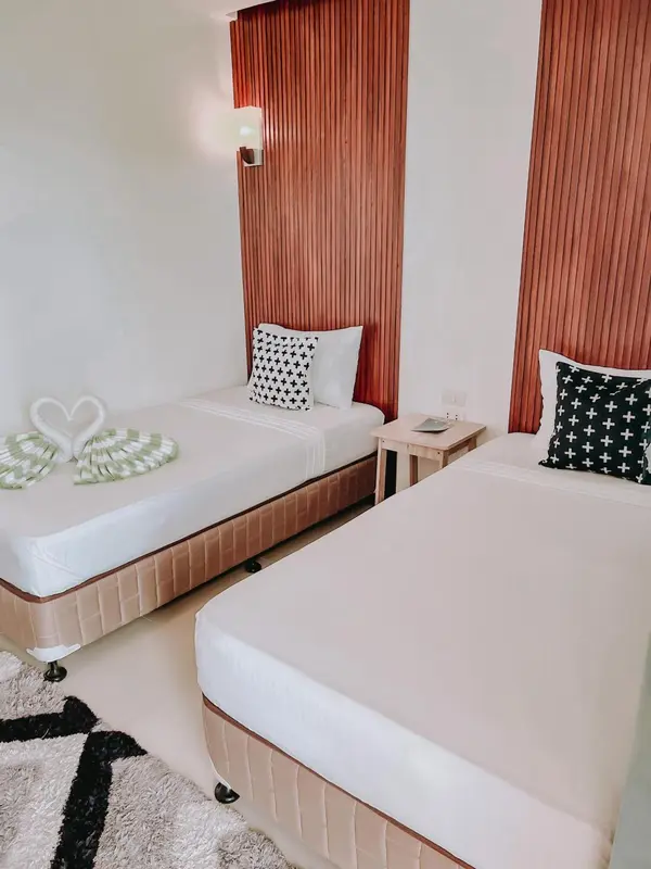 Deux lits simples avec une décoration florale sur les couvertures dans une chambre lumineuse.