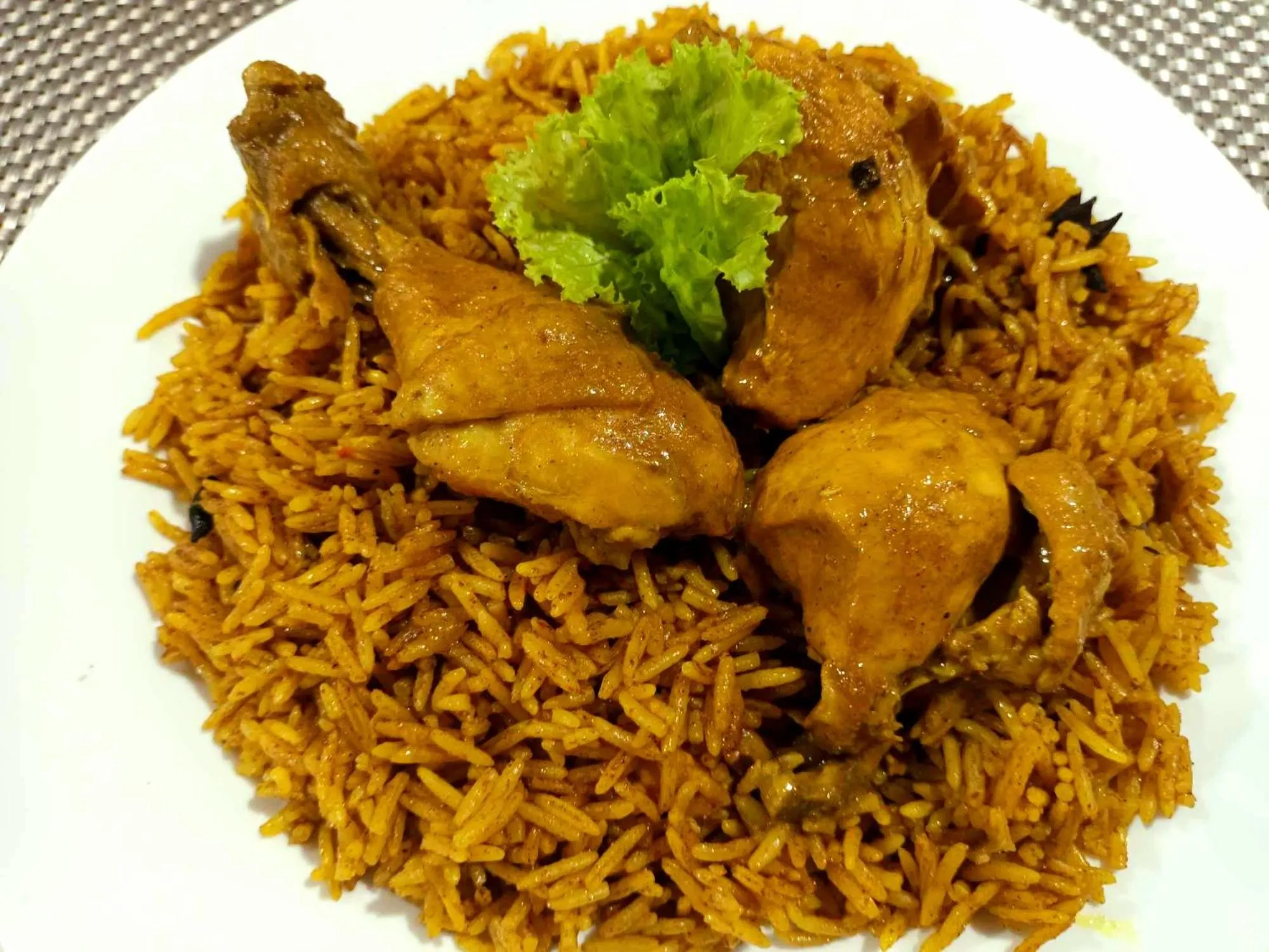 Assiette de riz safrané garnie de morceaux de poulet et d'une feuille de laitue.